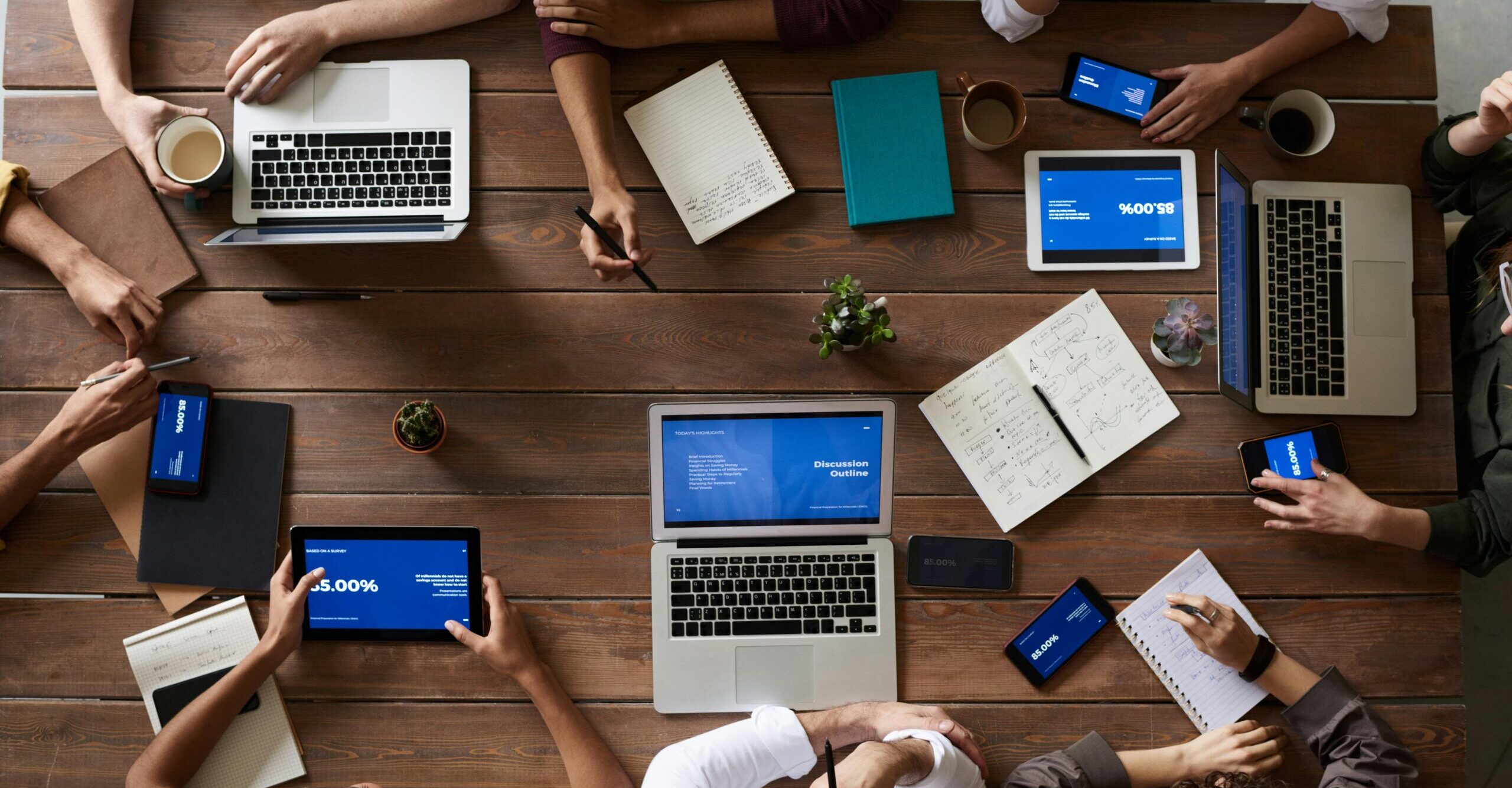 Overhead view of a diverse team in a business meeting using laptops and tablets.