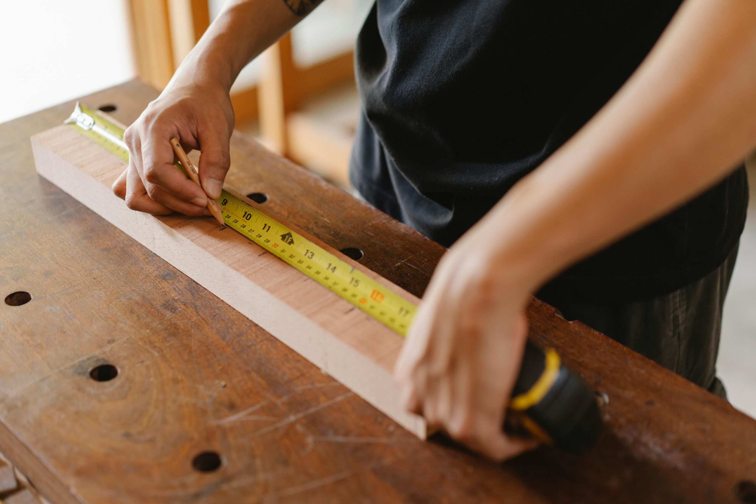 A craftsman measuring a wooden plank with precision in a workshop setting.